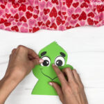 hand gluing the eyes of the grinch valentine craft