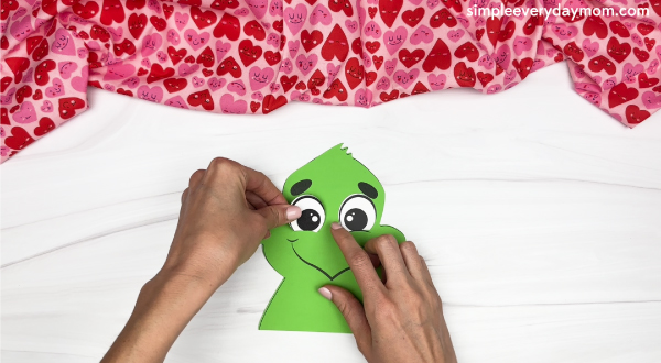 hand gluing the eyes of the grinch valentine craft