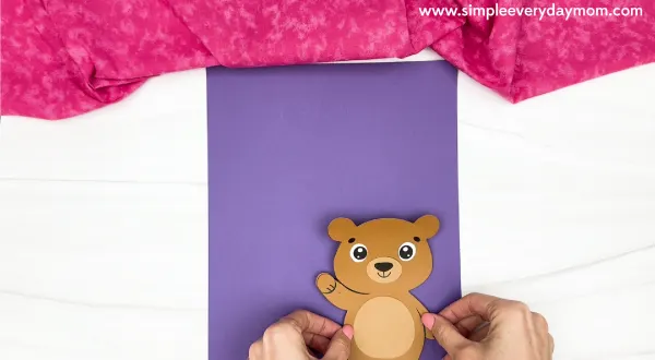 hand gluing the bear to the background paper