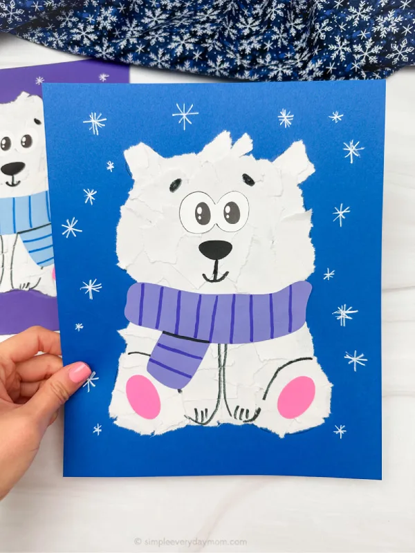 holding the torn paper polar bear craft. with background craft on the side