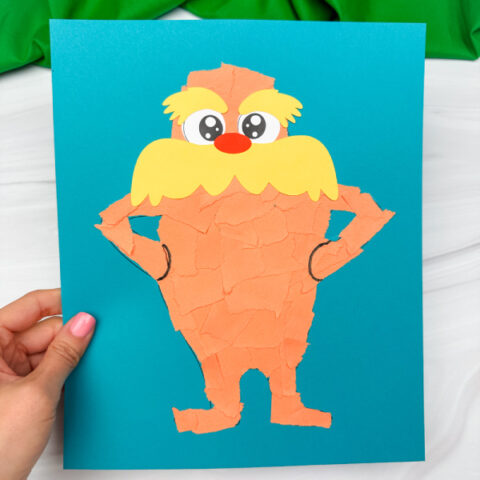 holding the torn paper lorax craft with green background