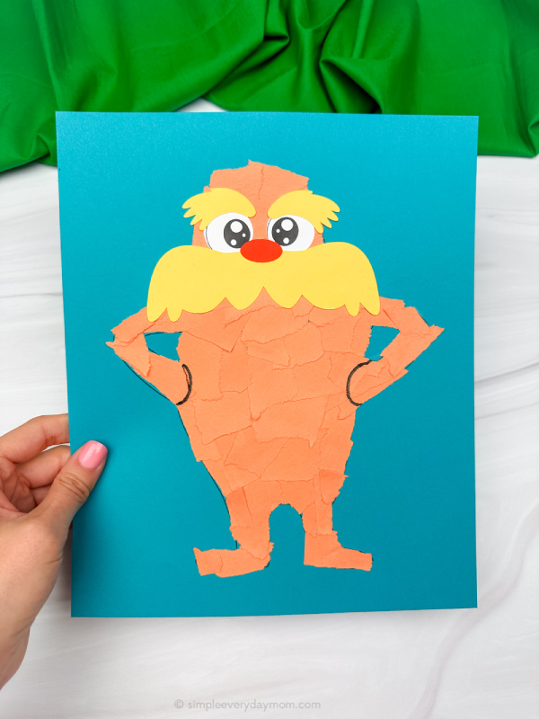 holding the torn paper lorax craft with green background