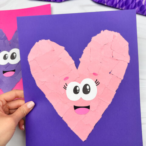 holding torn paper heart craft with background on side