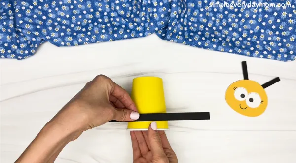 hand gluing the stripes at the bottom of the paper cup