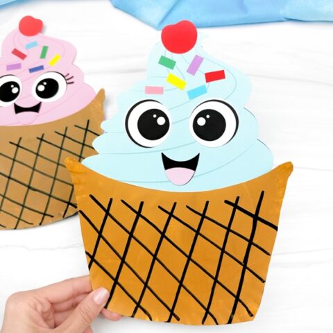 hand holding the paper plate ice cream craft with background on side.