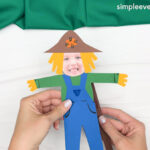 Hand gluing the pole of the Scarecrow Photo Craft