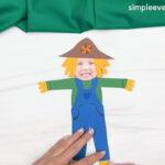 Hand gluing the straw on feet of the Scarecrow Photo Craft
