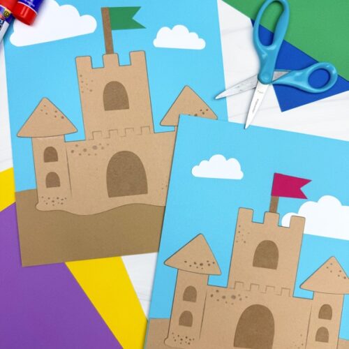 Two completed sandcastle paper crafts on a blue background with white clouds, one with a green flag and one with a red flag, surrounded by scissors, glue sticks, and colorful construction paper.