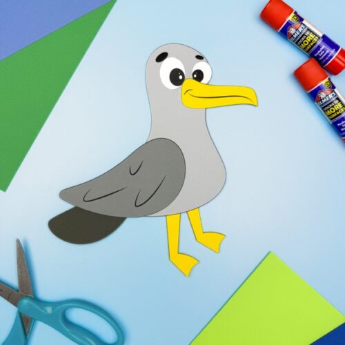 Completed paper seagull craft made from a free printable template, surrounded by scissors, glue sticks, and colored construction paper—ideal ocean-themed DIY project for preschool and kindergarten kids.