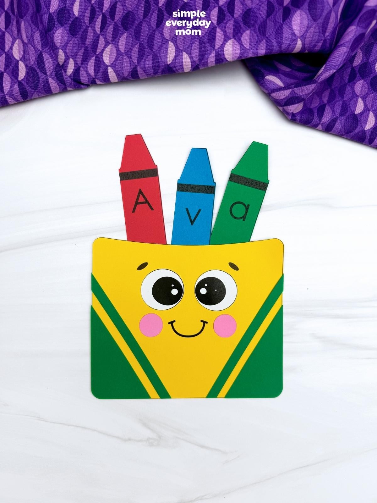 Finished crayon box name craft labeled “Ava” with three red, blue, and green crayons.