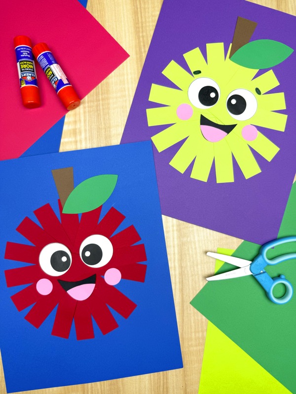 Two finished paper strip apple crafts, one red and one green, displayed on blue and purple backgrounds with smiling faces, surrounded by craft supplies like glue sticks, scissors, and colored paper.