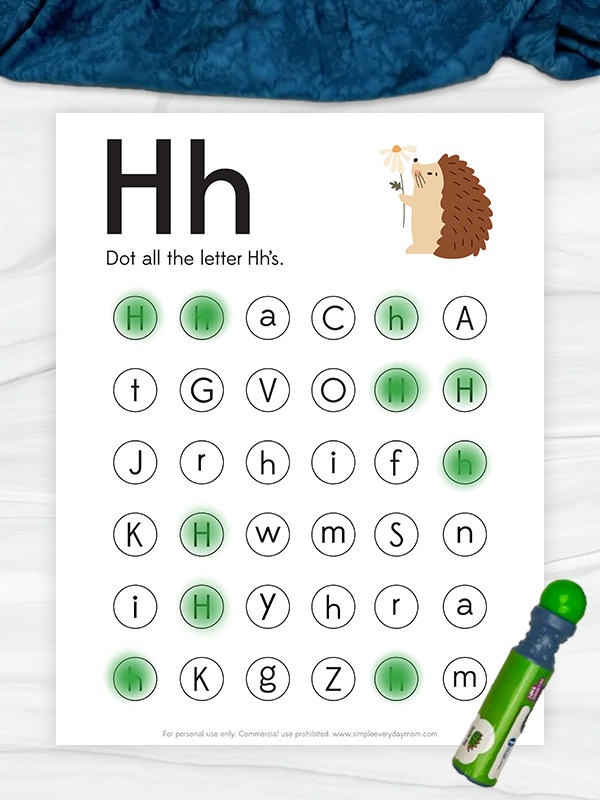 A children's worksheet focused on letter recognition, featuring uppercase and lowercase letters in circles. The instructions at the top say "Dot all the letter Hh's," and the letter H is highlighted with green dot marks throughout the page. An illustration of a hedgehog holding a flower is shown in the top right corner.
