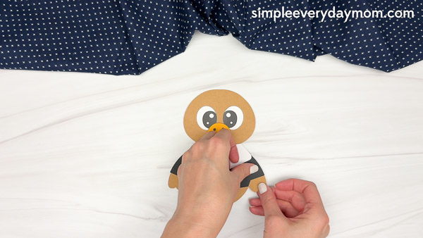 Hands sticking the wing onto the black shirt of the paper pilgrim craft.