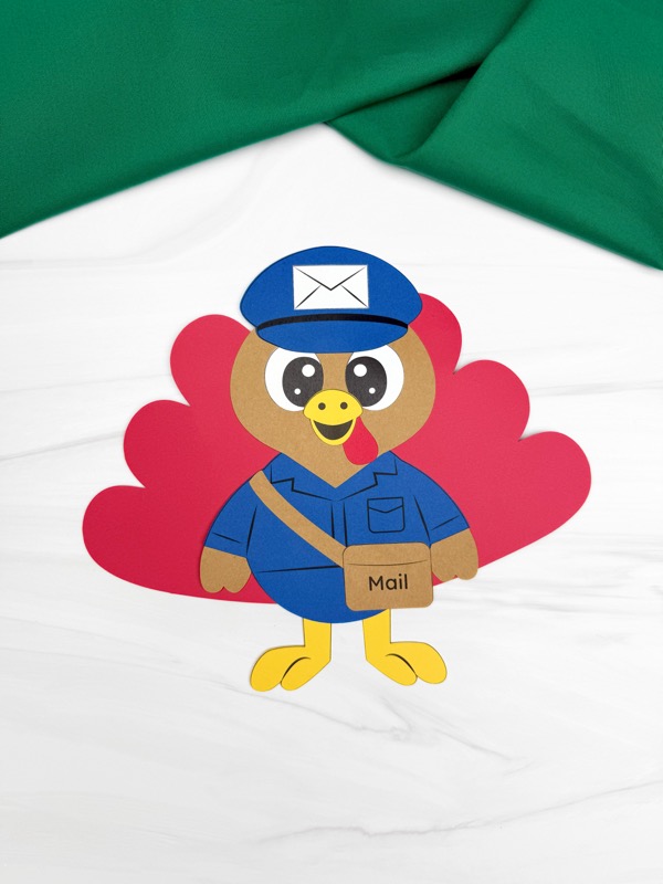 A completed Craft of a single paper mail carrier turkey with red feathers, a blue uniform, and a mailbag for a disguise a turkey project.