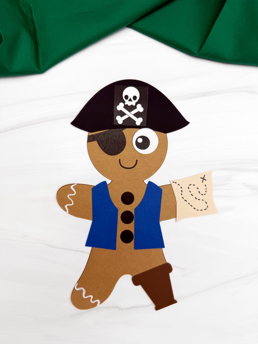 A completed Craft of a gingerbread man dressed as a pirate with a blue vest and treasure map.