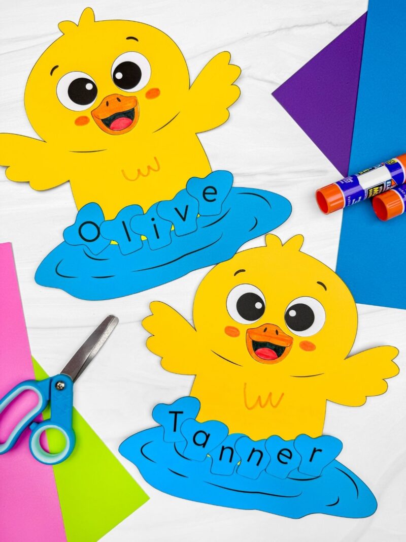 A completed craft showing two yellow duck name crafts with Olivia and Tanner on blue water, preschool spring literacy name activity with paper craft supplies for classroom use