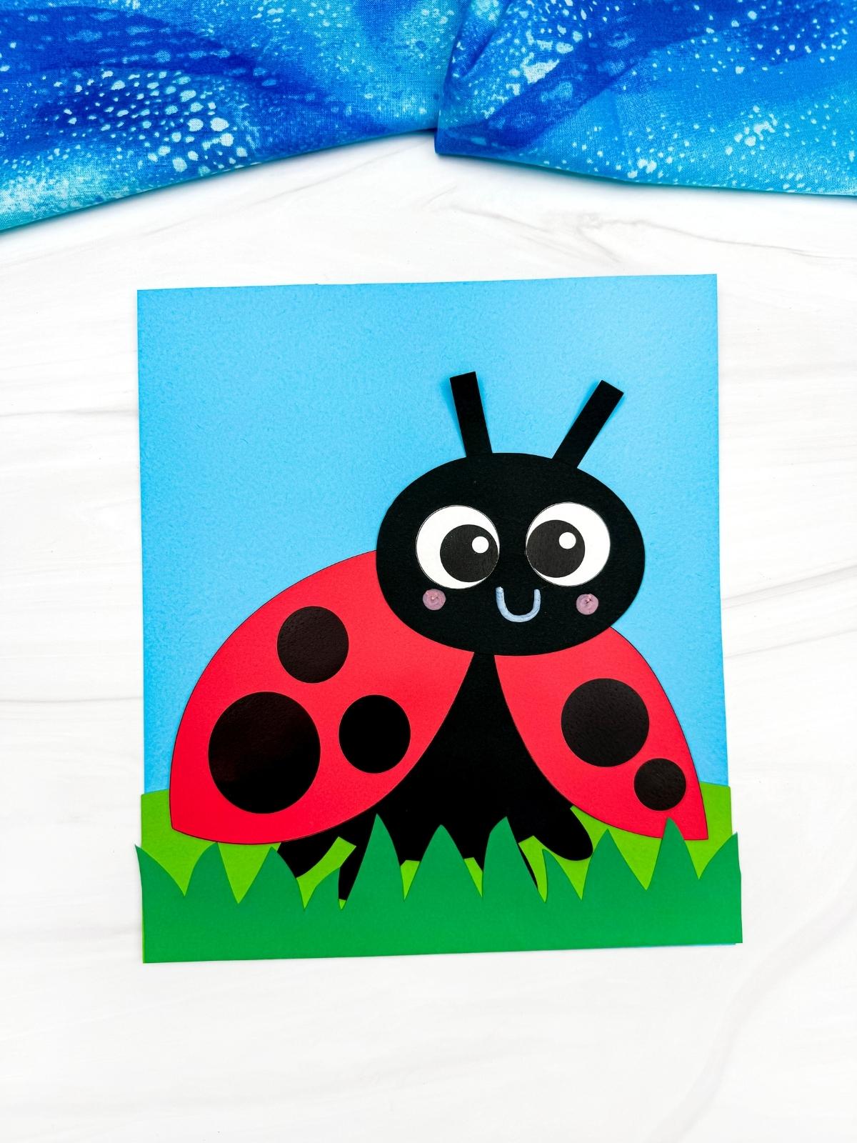 A completed craft of a cute ladybug paper craft on blue sky and green grass background for easy kids spring activity