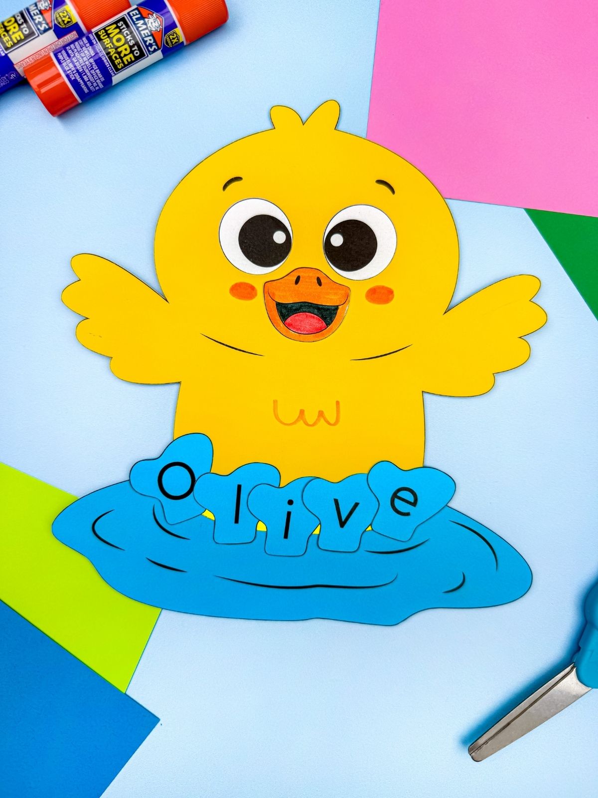 A completed craft showing a yellow duck name craft with Olivia on blue water, preschool spring literacy name activity with colorful paper and classroom craft supplies