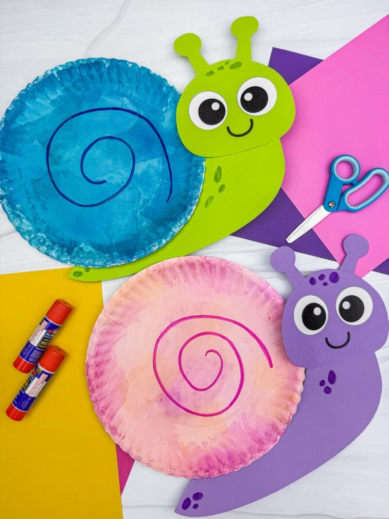 A completed snail paper plate craft with colorful shells, craft paper, scissors, and glue for a fun kids snail craft activity.
