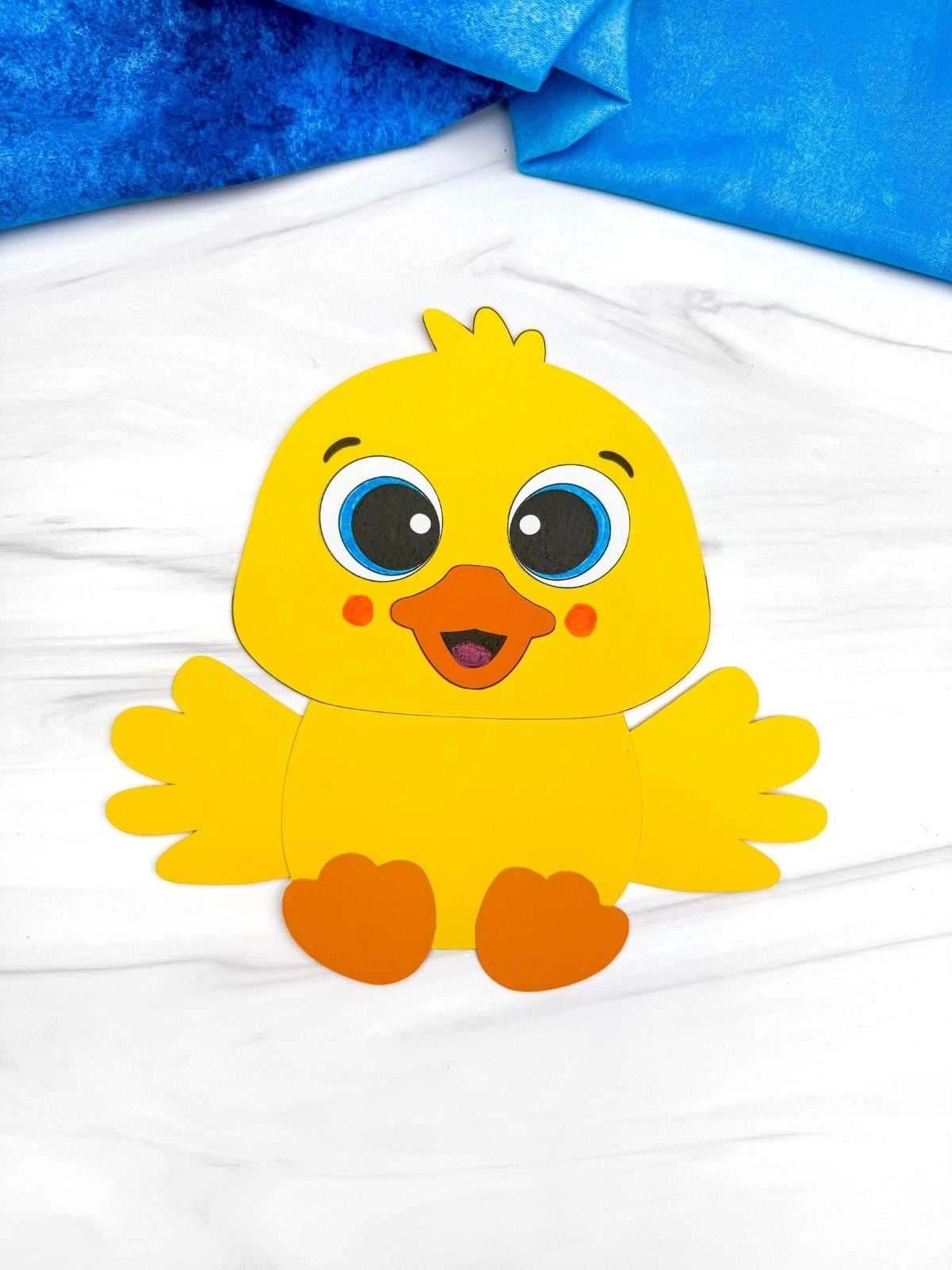 A completed craft showing a yellow baby duck paper craft with orange beak and feet for a kids spring craft.