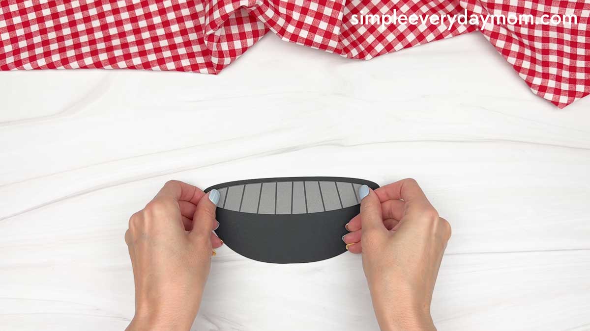 Hands holding a cut out grill base piece with grill lines for a Father’s Day craft