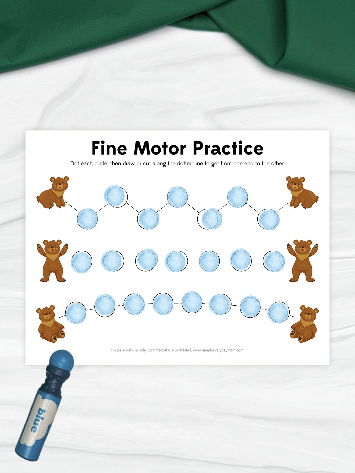 The image shows a “Fine Motor Practice” worksheet featuring small bear illustrations and a series of dotted paths made of circles. The circles are filled in with a blue dot marker, and children are encouraged to trace or cut along the lines from one bear to another. A blue dot marker is placed beside the page, highlighting the hands-on learning activity.