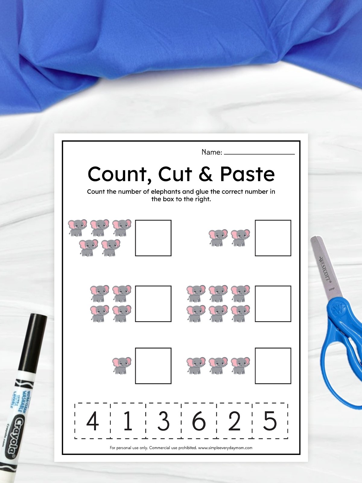 The image shows a children’s worksheet titled “Count, Cut & Paste” designed for practicing counting skills. It features groups of small cartoon elephants with empty boxes beside them where the correct number should be placed. At the bottom, there are cut-out numbers, along with a pair of scissors and a marker visible on the side, suggesting a hands-on activity.