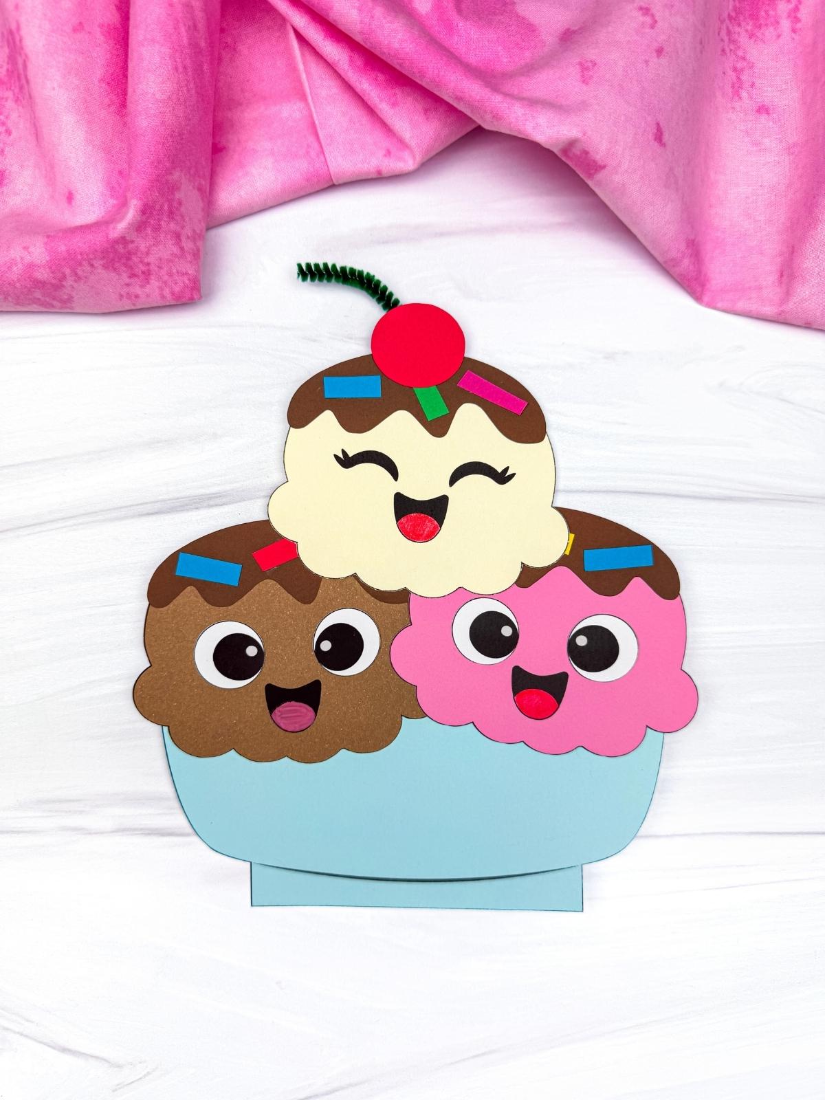 A completed craft of a smiling ice cream sundae with three colorful scoops and a cherry on top