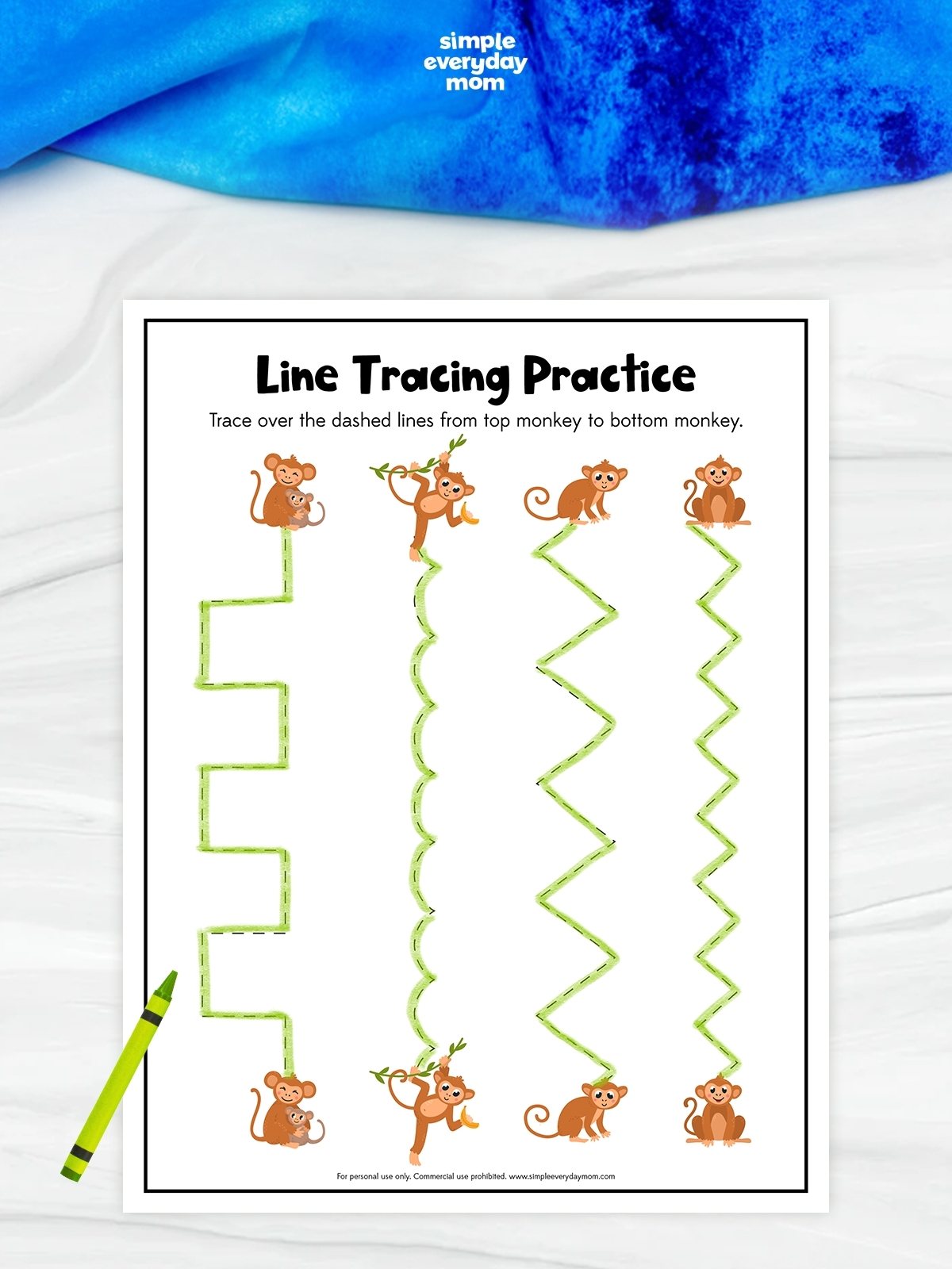 This image shows a preschool printable worksheet titled “Line Tracing Practice” featuring cute monkey illustrations. Children are instructed to trace over dashed lines from the top monkey to the matching monkey at the bottom. The worksheet includes four different tracing patterns: a stepped line, a wavy line, a large zigzag line, and a smaller zigzag line. A green crayon is placed beside the worksheet, and the overall design is playful and aimed at helping young children develop fine motor and pre-writing skills.