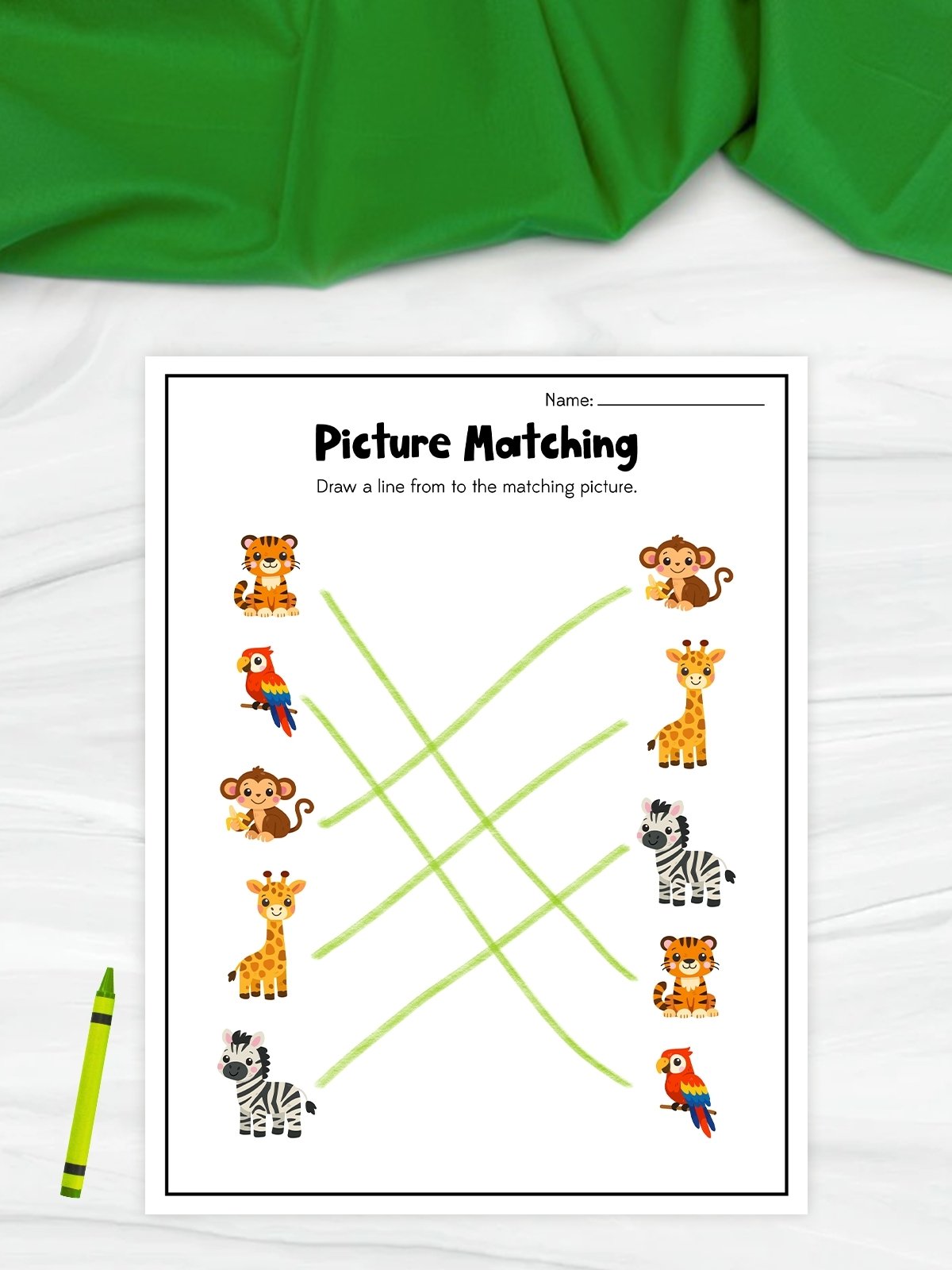 This image features a printable “Picture Matching” worksheet that helps young children practice visual recognition and matching skills. The worksheet displays pairs of colorful animals, including a tiger, parrot, monkey, giraffe, and zebra, with light green lines connecting each matching picture. A bright green crayon beside the page and the cheerful cartoon illustrations create a fun and engaging educational activity for preschool learners.