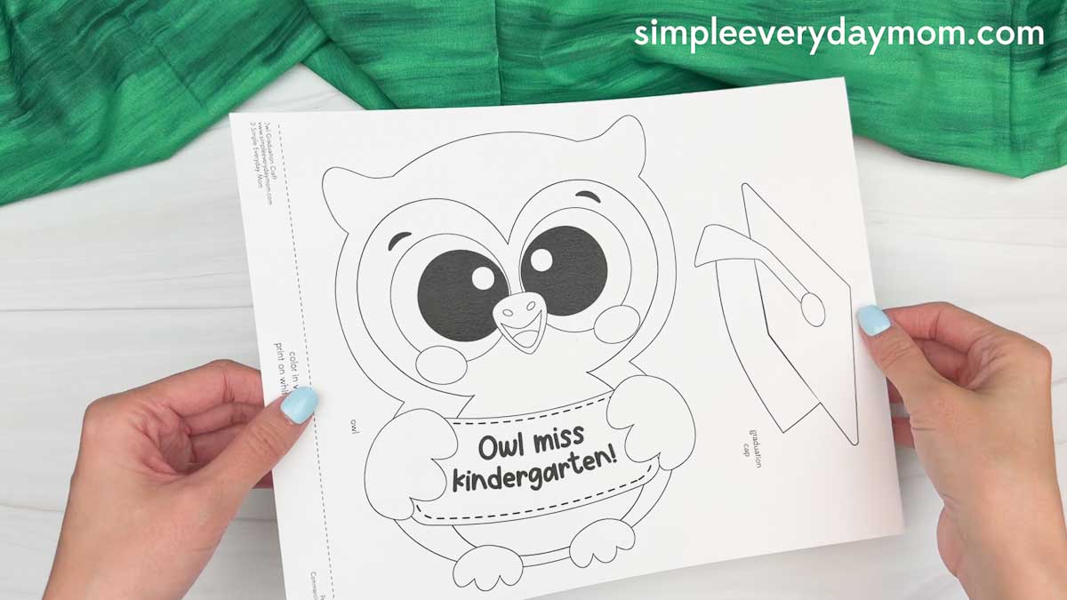 Hands holding the owl graduation craft template with printable owl pieces and graduation cap outlines.