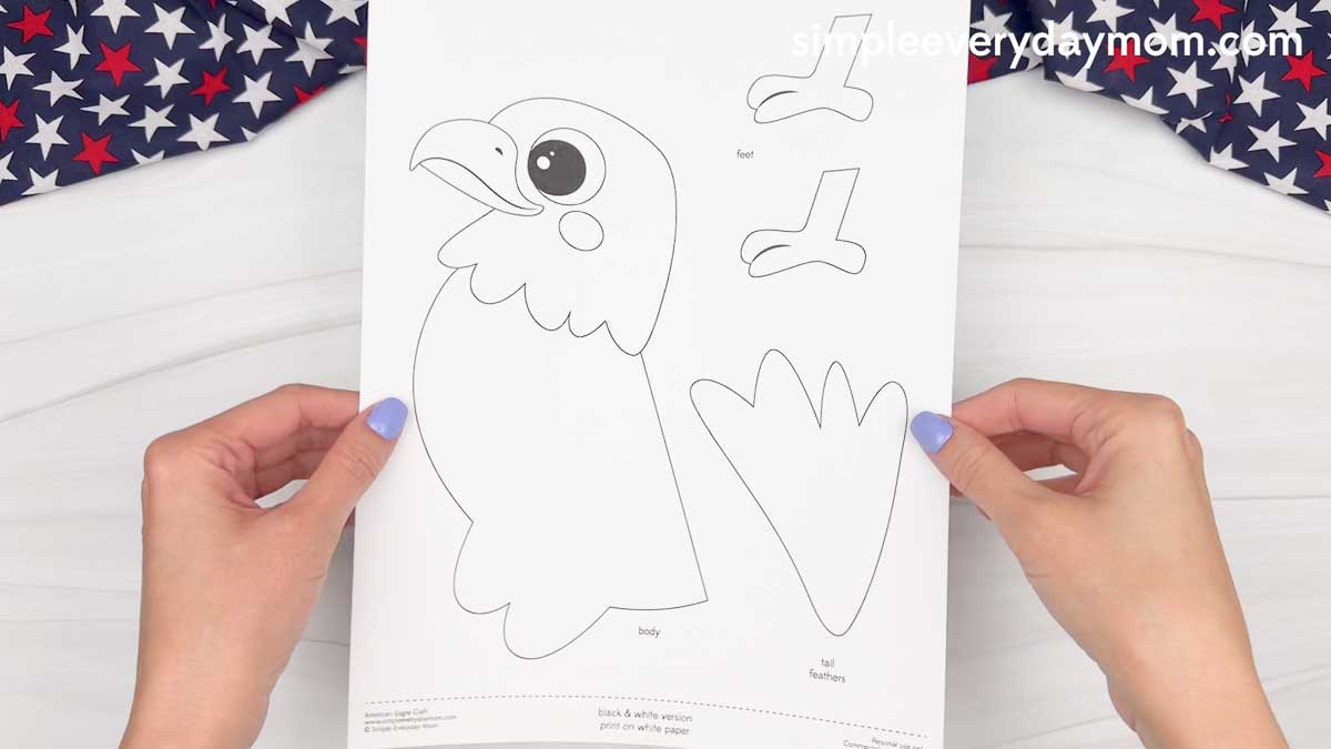 Hands holding a printed American eagle handprint craft template with eagle body, feet, and tail feather cutout pieces.