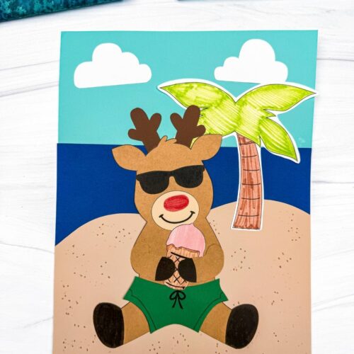 A completed craft featuring a reindeer in sunglasses and green swim trunks holding an ice cream cone on a beach scene background with a palm tree and clouds.