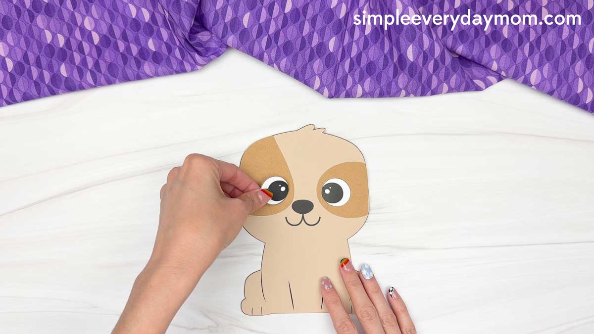 Hands placing an eye onto a paper puppy craft for a Father's Day dog craft activity
