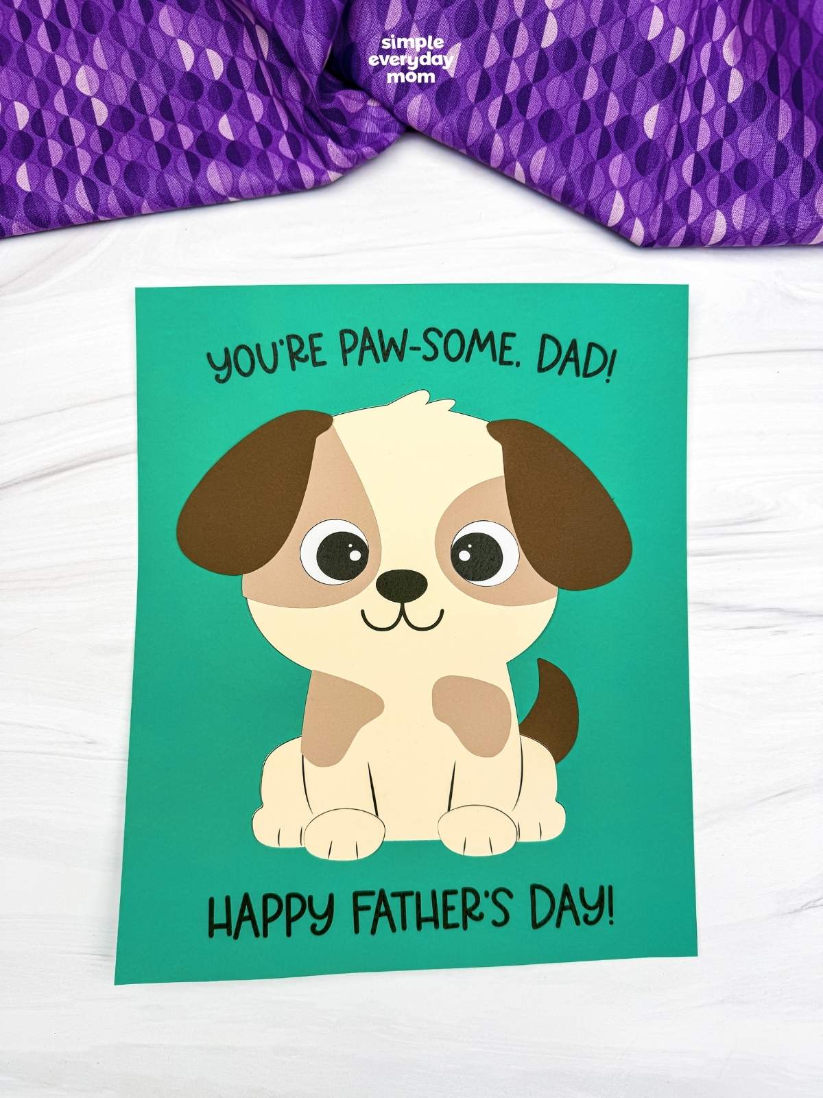 A completed craft featuring a puppy Father’s Day card with a paw-some message on a green background for kids to make dad