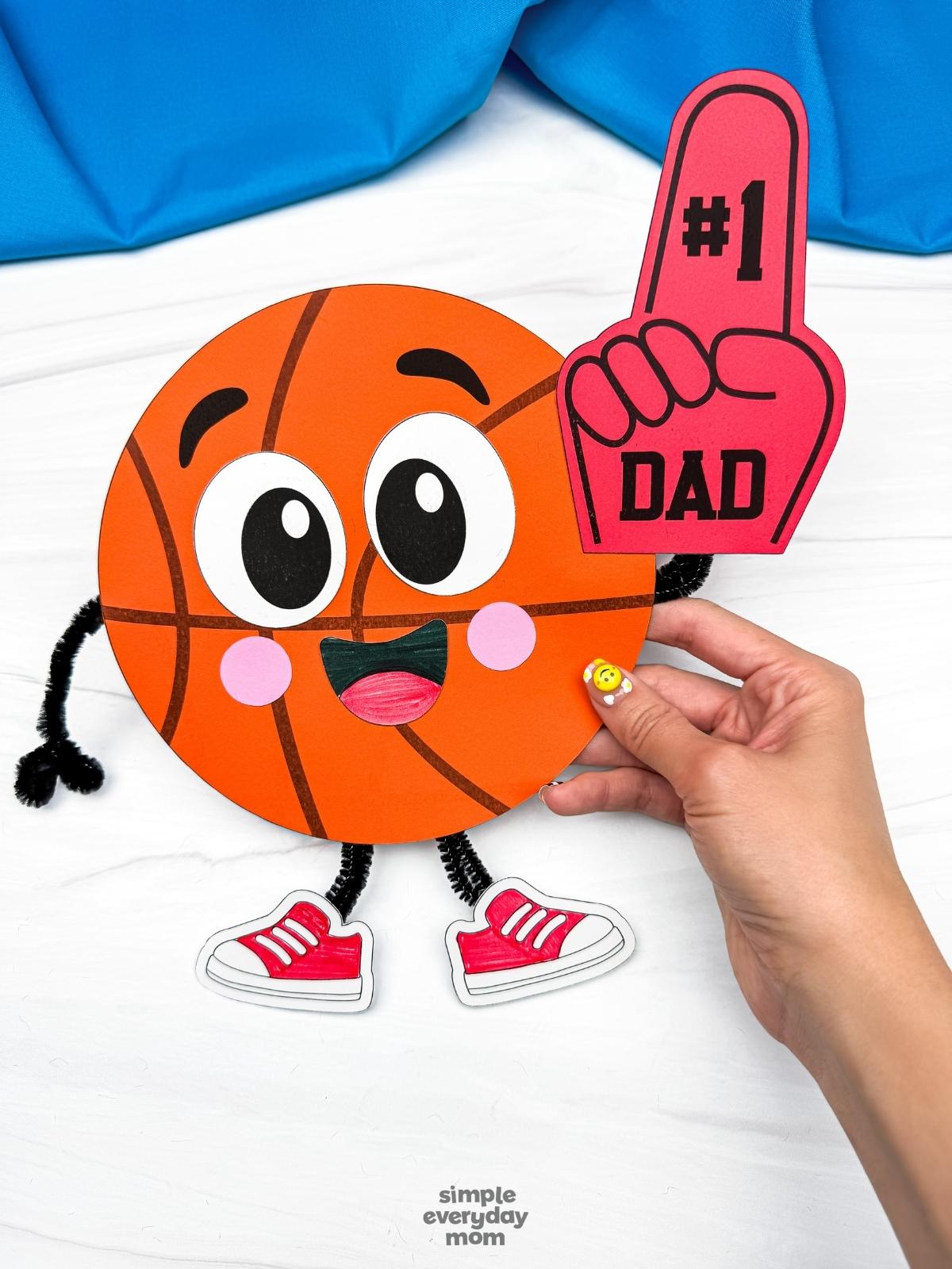 A completed craft of a basketball Father’s Day character holding a number one dad foam finger.