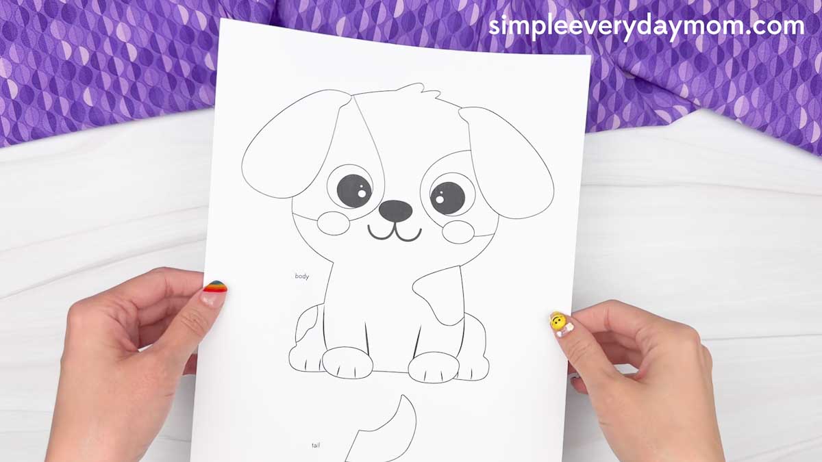 Hands holding a printable puppy craft template with cutout pieces for a Father's Day dog craft activity