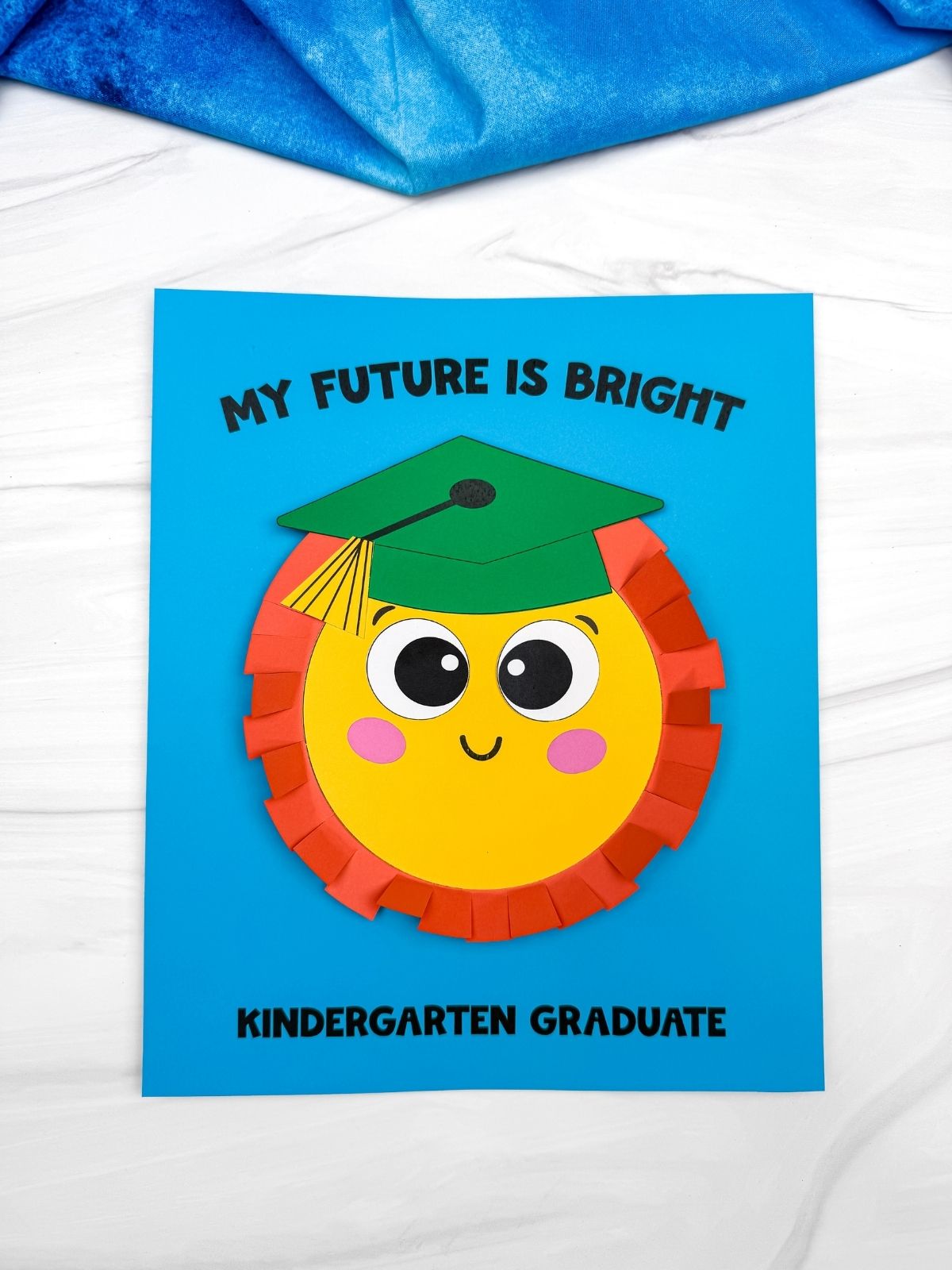 A completed craft sun graduation card with a smiling sun wearing a green graduation cap and “My Future Is Bright” text on blue paper