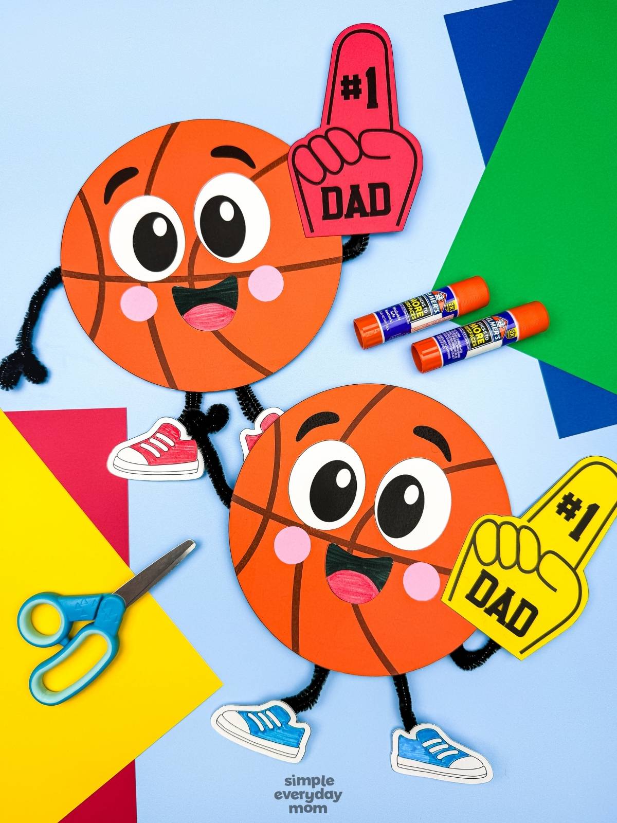 A completed craft of two basketball Father’s Day characters with foam fingers surrounded by colorful craft supplies.