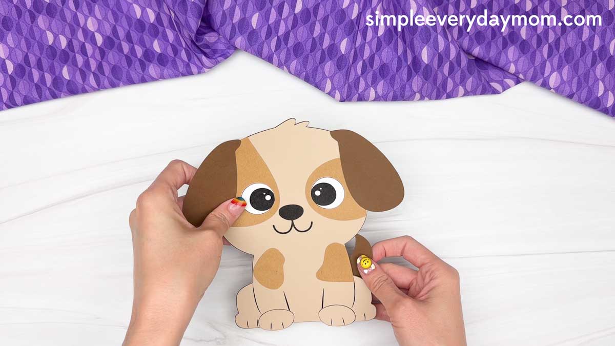 Hands attaching the tail to a completed paper puppy craft for a Father's Day dog craft activity