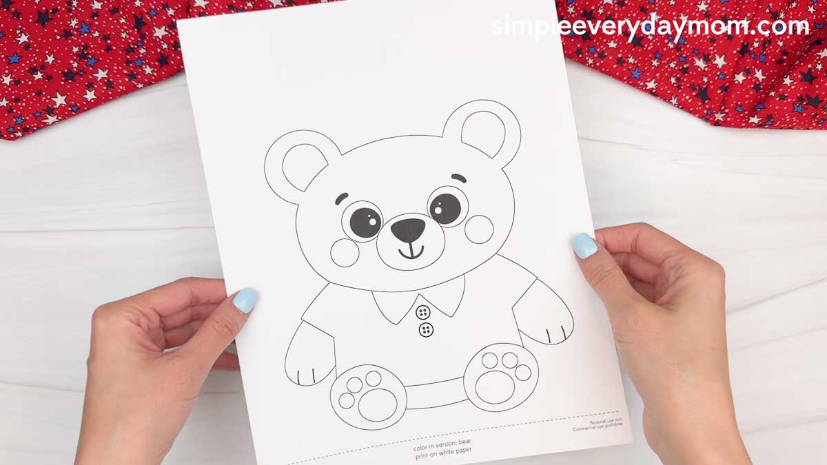 Hands holding a printable teddy bear craft template on white paper for a patriotic teddy bear craft activity
