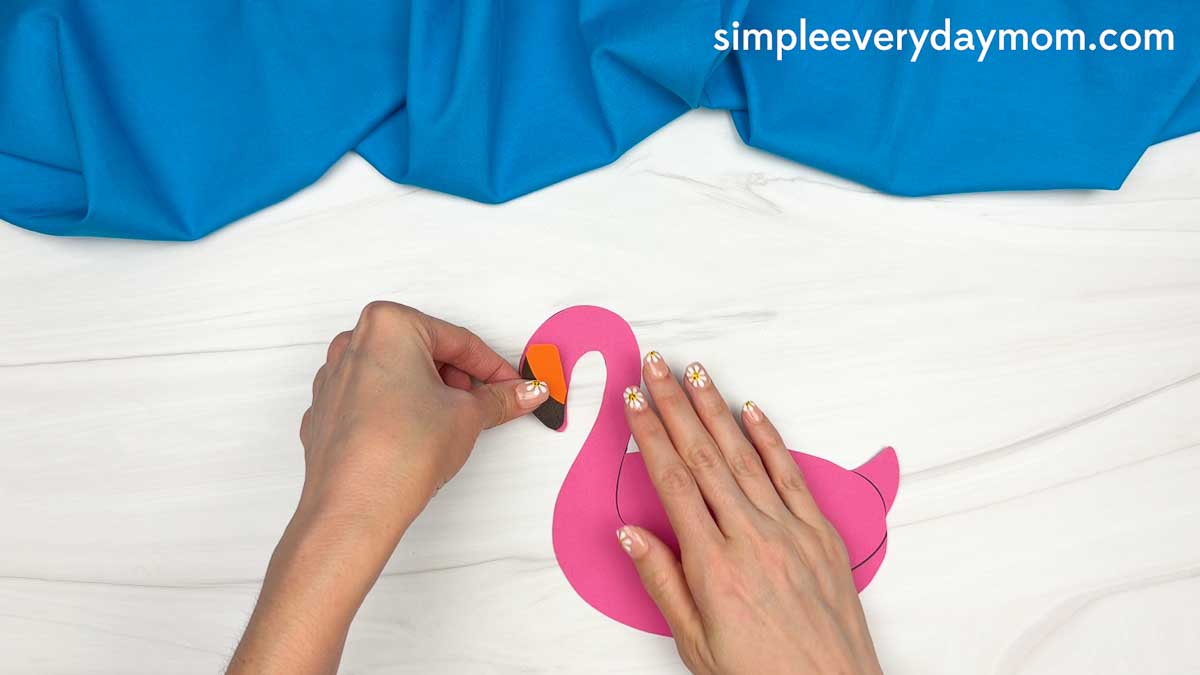 Hands assembling a pink flamingo pool float for the Summerween ghost craft.