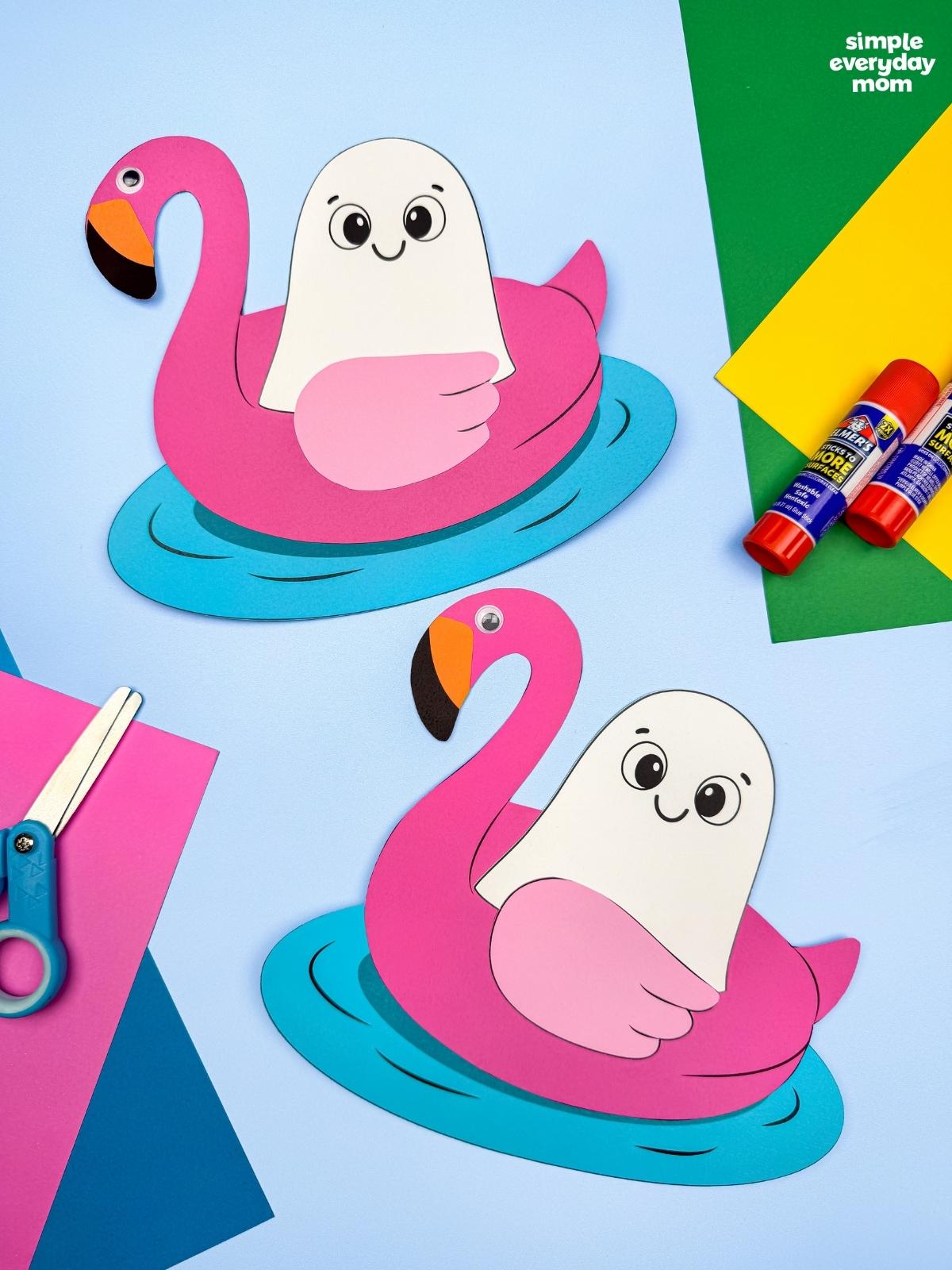 A completed craft showing two Summerween ghosts floating in pink flamingo pool floats with colorful craft supplies.
