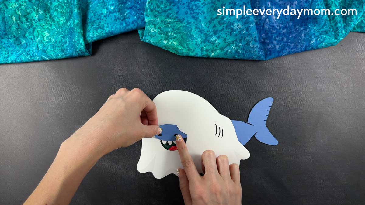 Hands attaching the blue shark snout piece to the front of a ghost shark craft.