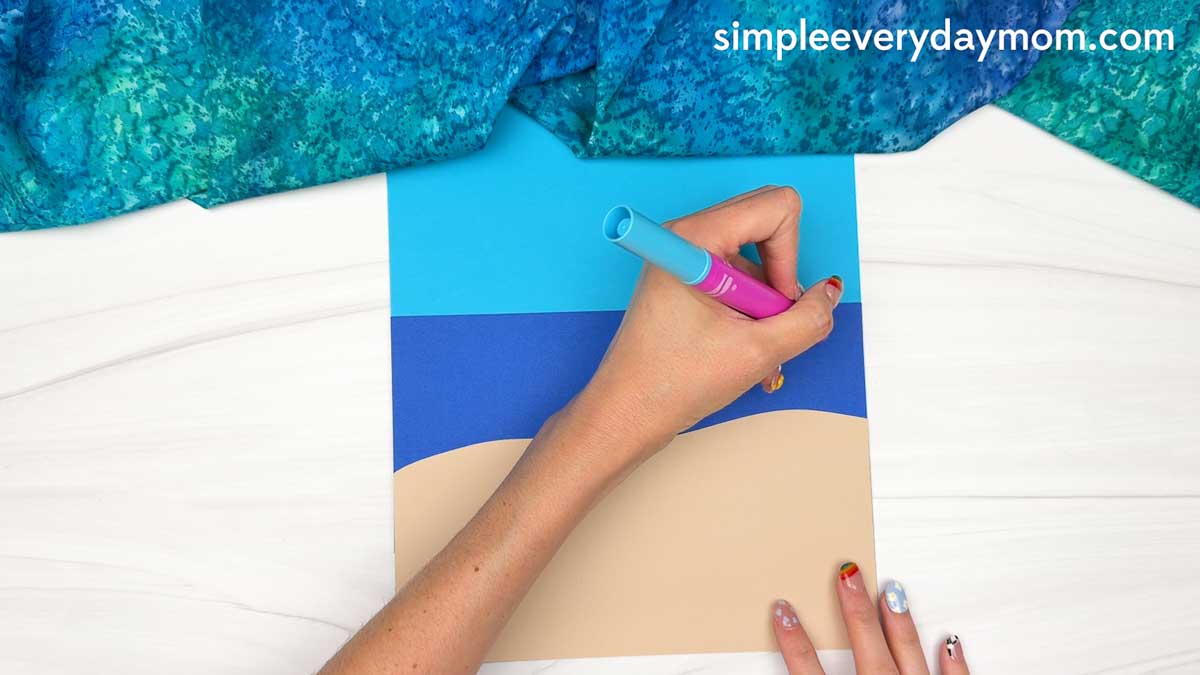 Hands drawing wave details on the ocean background for the Summer Mrs. Claus craft.