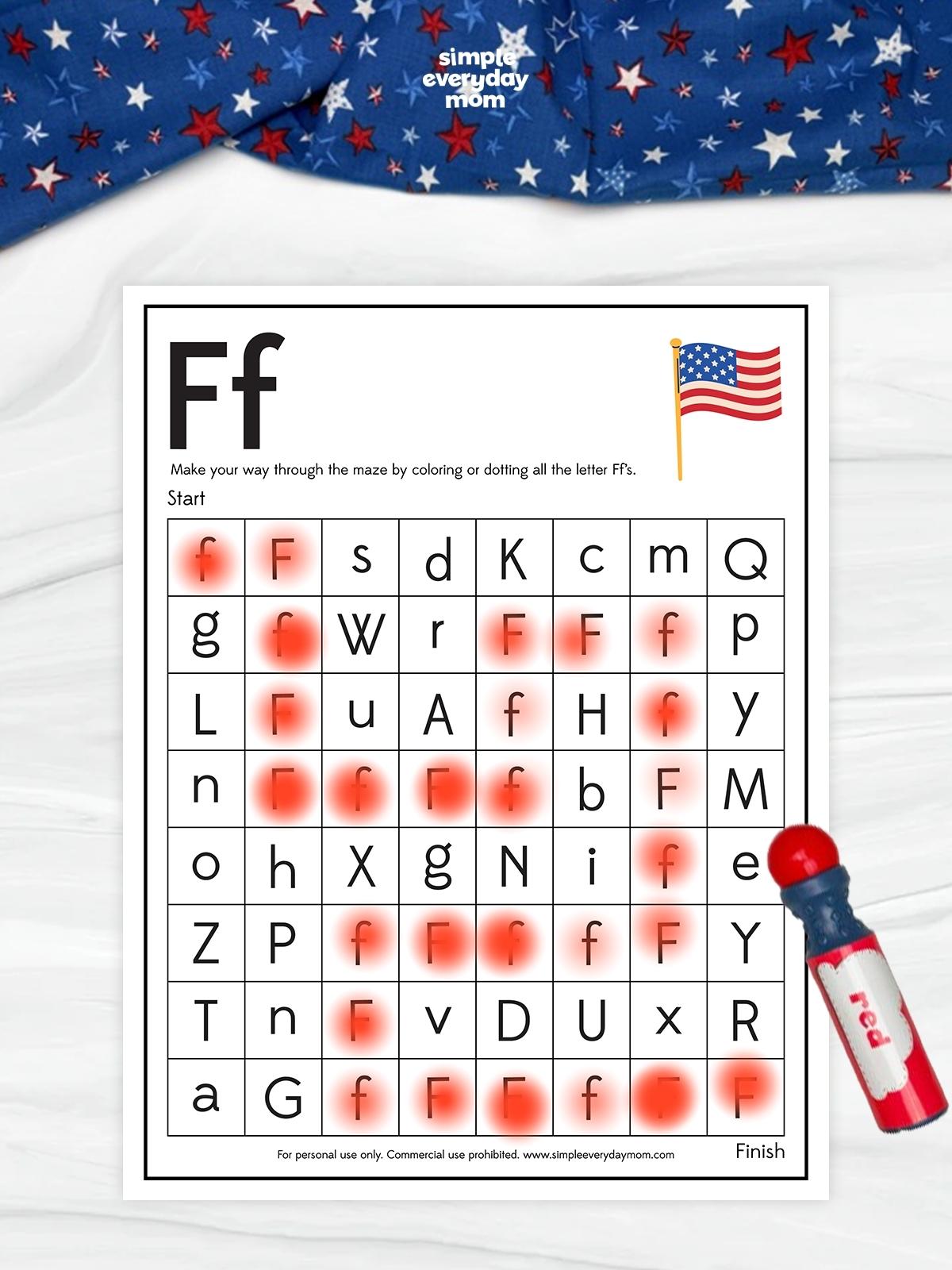 This image features a July 4th-themed alphabet maze worksheet centered on the uppercase and lowercase letter F. Children navigate through the maze by coloring or dotting only the letter F's, helping improve letter recognition, concentration, and visual tracking skills. The patriotic design includes an American flag and festive red, white, and blue decorations, making it a fun literacy activity for Independence Day celebrations.