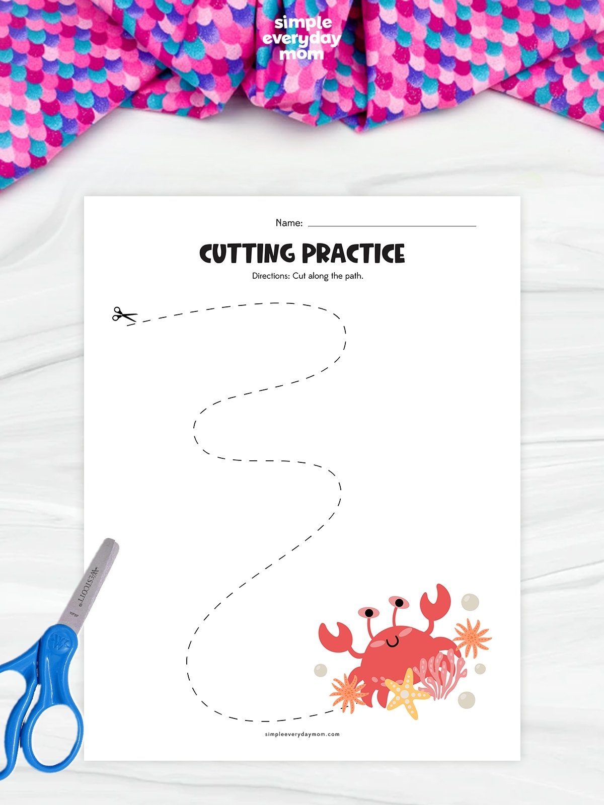 This image shows an ocean-themed cutting practice worksheet designed to help young children build scissor control and fine motor skills. A long dashed, winding path leads from a pair of scissors at the top of the page to a cheerful crab surrounded by seashells, coral, and starfish at the bottom. The simple design encourages kids to practice cutting along curved lines while enjoying a fun under-the-sea theme.