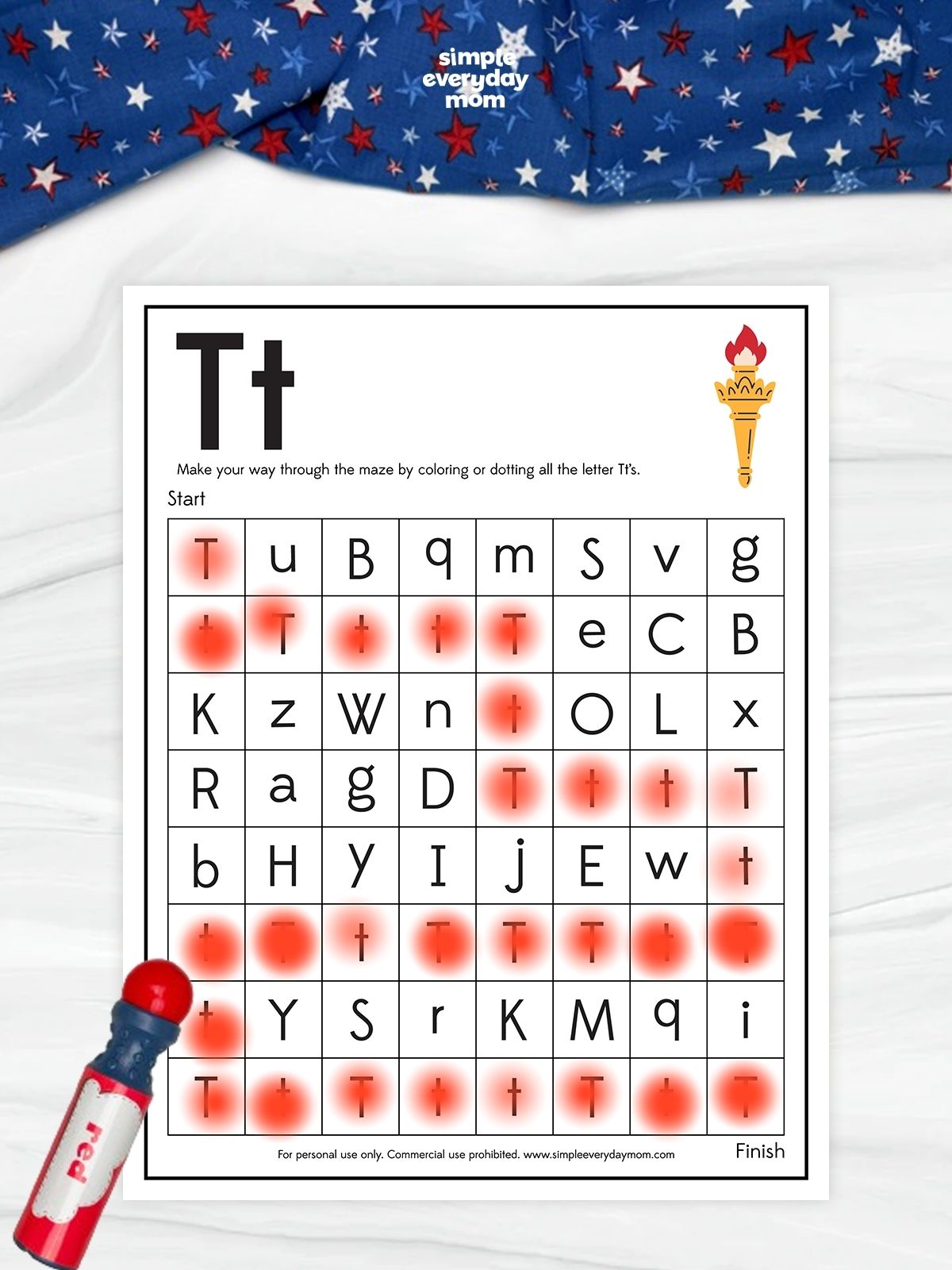 This image shows a July 4th-themed alphabet maze worksheet focused on the uppercase and lowercase letter T. Children follow a path through the maze by coloring or dotting only the letter T's, helping strengthen letter recognition, visual discrimination, and early literacy skills. The patriotic design, featuring a torch icon and red, white, and blue decorations, makes learning fun while celebrating Independence Day.
