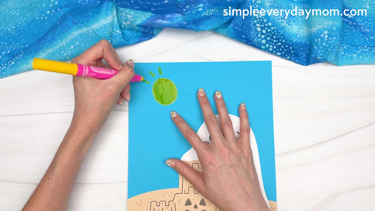 Hands drawing a bright sun in the sky above the beach ghost craft scene.