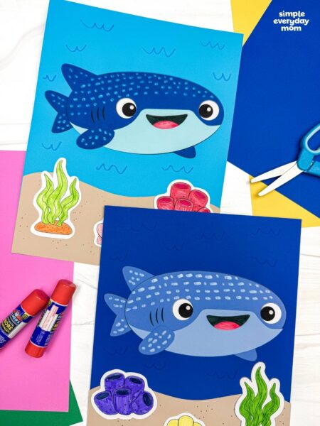 A completed Craft showing two whale shark paper crafts on ocean themed backgrounds with seaweed, coral, and colorful craft supplies nearby.